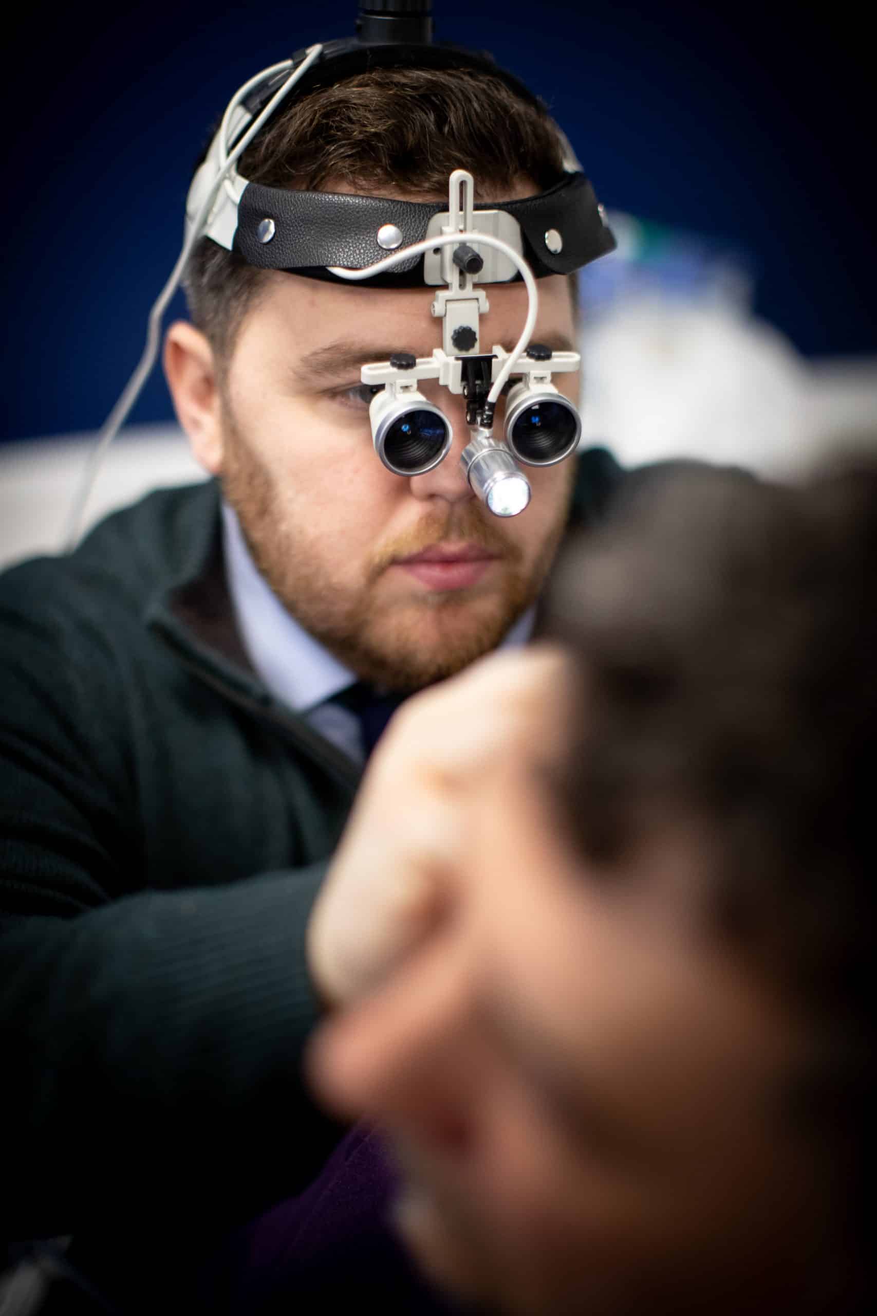 Audiologist performing professional ear wax removal with specialist equipment at Kensington Hearing London.